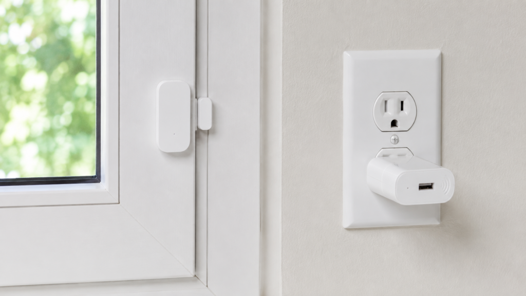 Aqara MCCGQ11LM contact sensor aligned across a casement window beside an IKEA E1746 Zigbee signal repeater.